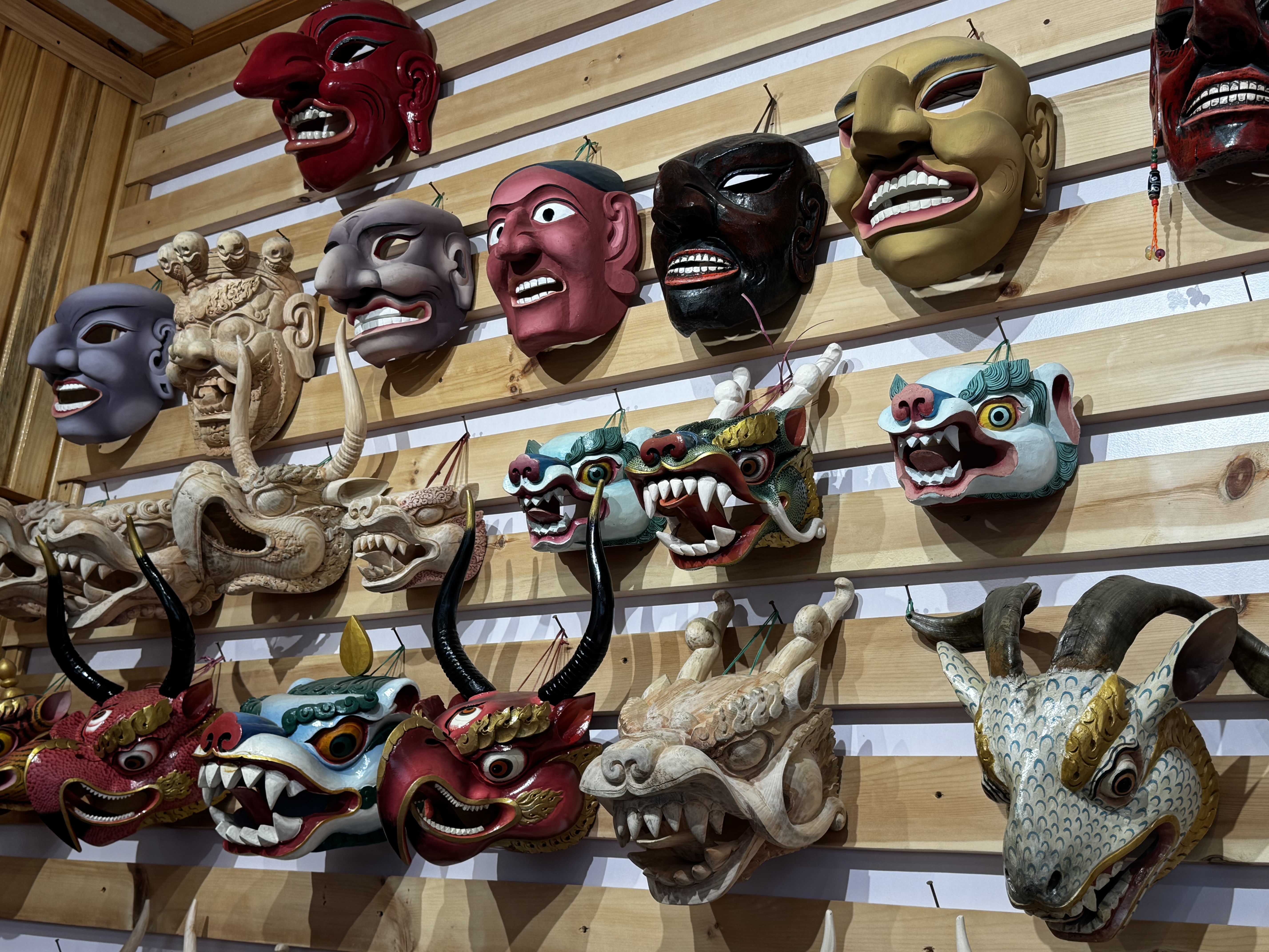 A wall of masks at the art gallery — the range of expression is striking